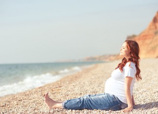 Mujer embarazada reposando en la playa